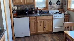 Una cocina con armarios de madera, estufa, lavaplatos y una ventana con persianas.