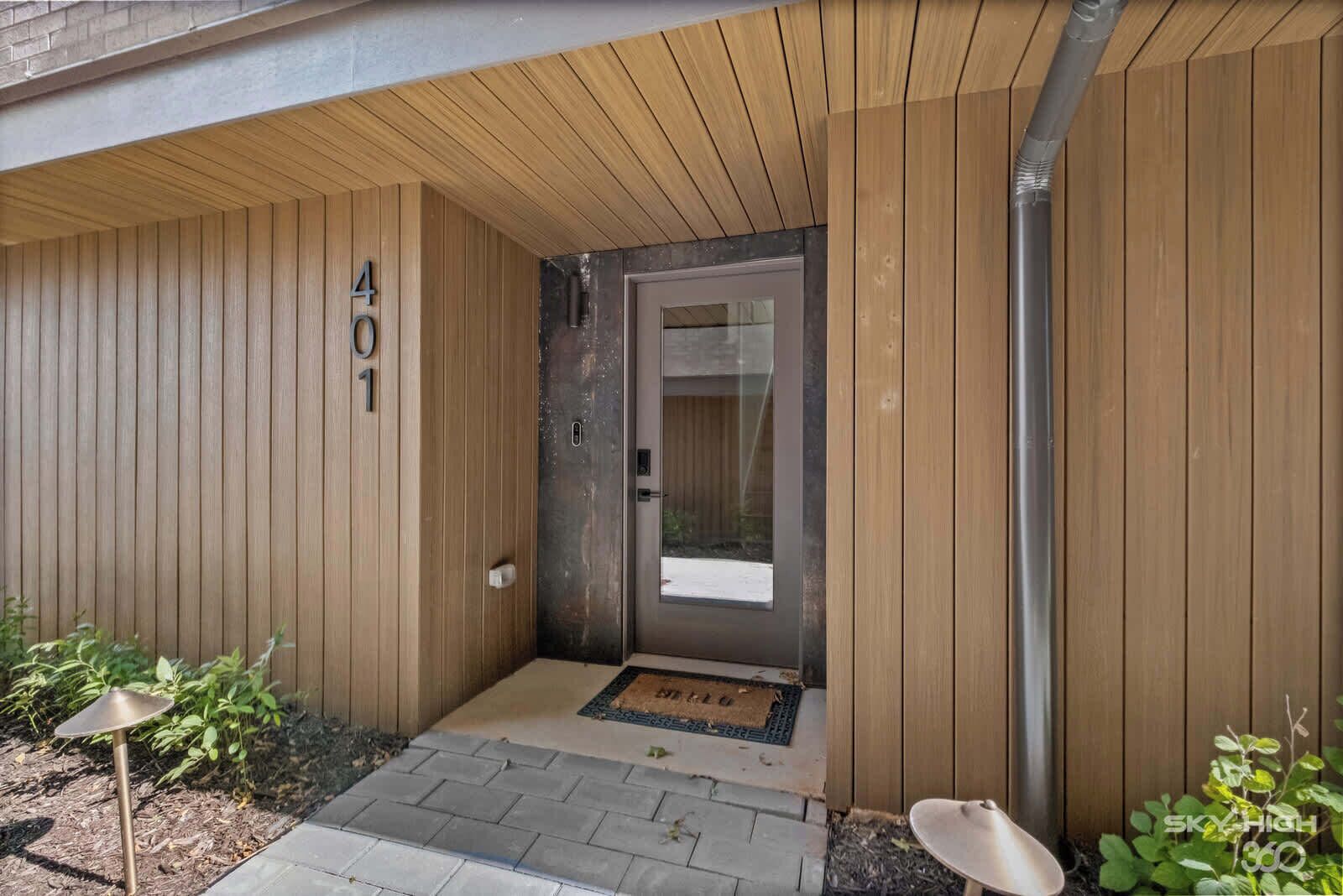 A wooden exterior with a door marked '401' and a small outdoor area with a doormat.