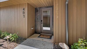 Une façade en bois avec une porte portant le numéro « 401 » et un petit espace extérieur agrémenté d’un paillasson.