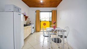 Eine kleine Küche mit Mikrowelle, Kühlschrank und einer Essecke mit Tisch und Stühlen.