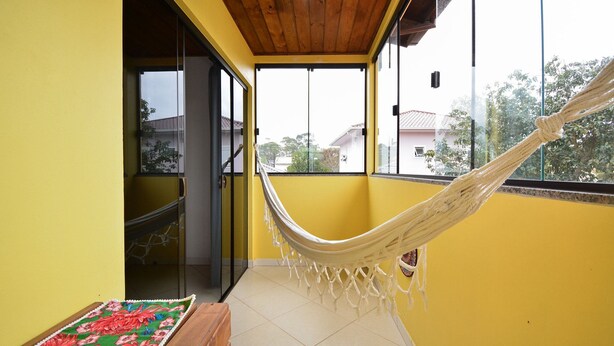 Una habitación con una hamaca, un banco de madera y un colorido tapete.