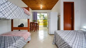 Una habitación con dos camas, techo de madera, comedor y puerta que da al exterior.