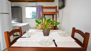 Una mesa de comedor con mantel blanco, una planta en maceta y un juego de cubiertos.