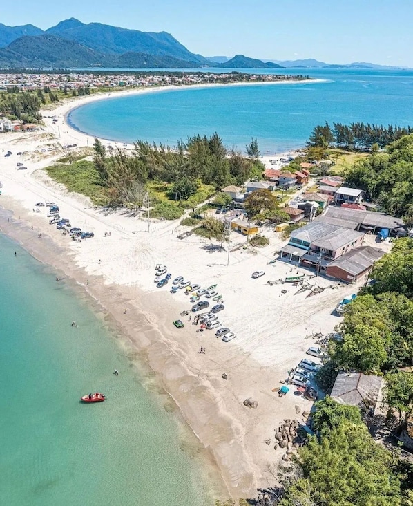 Vista aérea de una zona costera con playa, un bote pequeño y edificios.