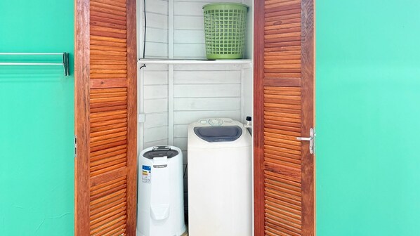 Un lavadero pequeño con contraventanas de madera, una lavadora y una secadora.