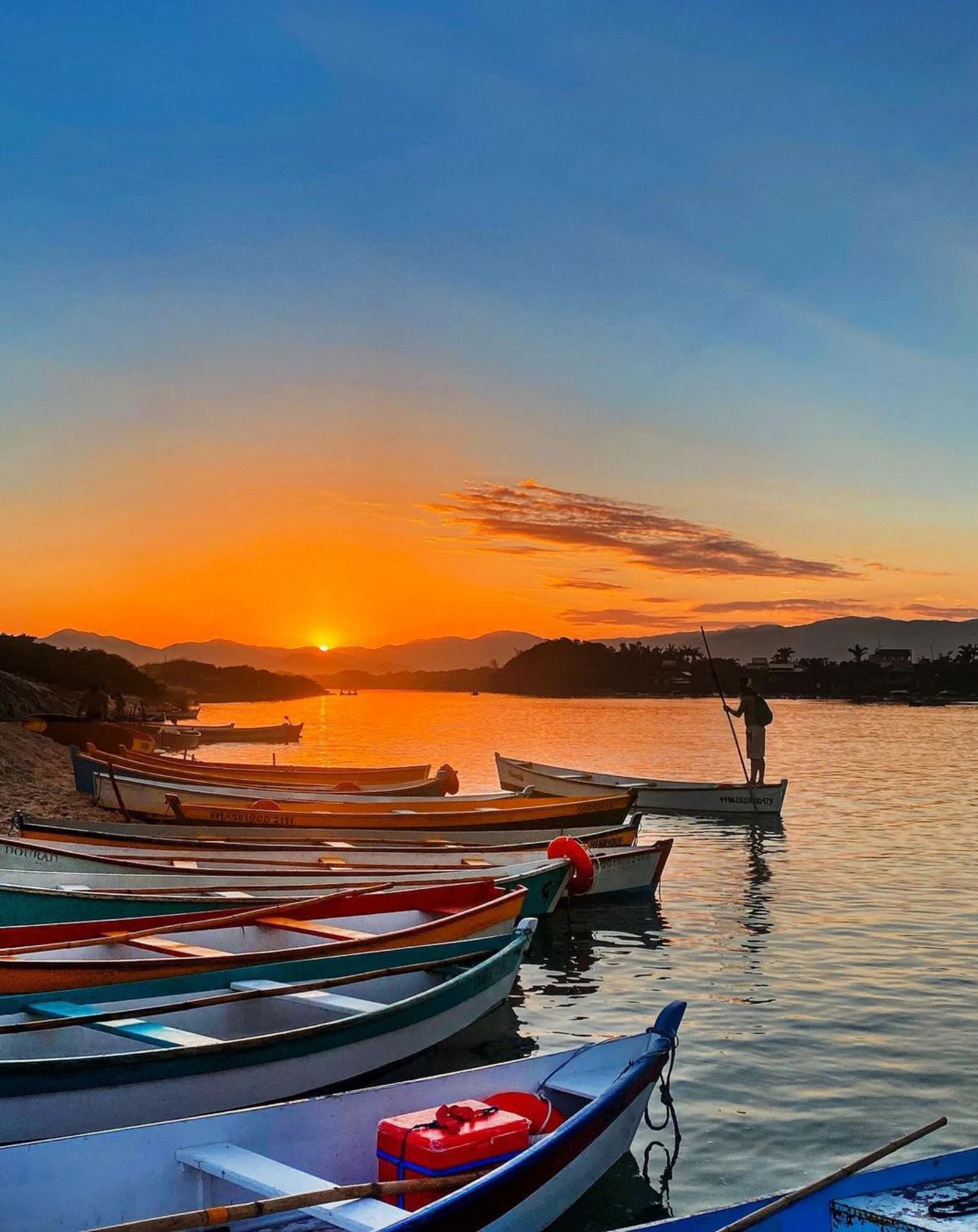 Een zonsondergang met boten in een jachthaven.