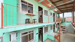 A multi-story building with a green exterior, multiple balconies, and a staircase.