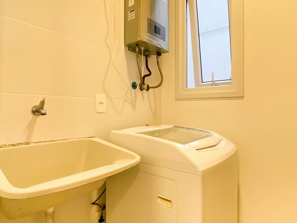 A bathroom with two sinks, a window, and a water heater.