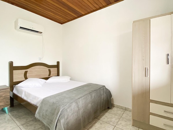 A bedroom with a wooden bed, a wardrobe, and an air conditioning unit on the wall. - Penthouse - Resid. Green Seas (Bombinhas)