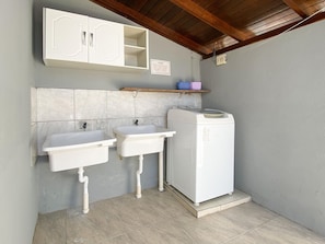 A bathroom with two sinks, a washing machine, and a cabinet above the sinks. - Penthouse - Resid. Green Seas (Bombinhas)