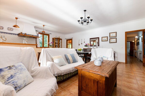 A spacious living room with a wooden coffee table, a white sofa, and a dining table.