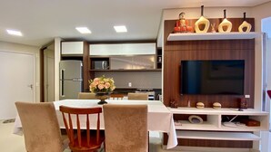 Una cocina moderna con televisor integrado, un comedor con sillas y un jarrón decorativo sobre la mesa.