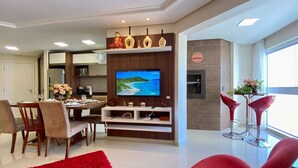 Una sala de estar moderna con televisor, comedor y sillas rojas.