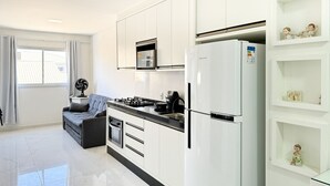 A modern kitchen with white cabinetry, a built-in oven, and a refrigerator.