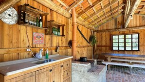 Ein rustikales Holzinterieur mit Küchenbereich, Holzschnitzschränken, einem Spülbecken und einem Esstisch.