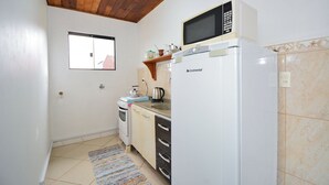 Eine kleine Küche mit Mikrowelle, Kühlschrank, Backofen und einem Fenster.