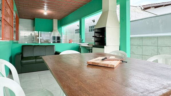 Una cocina moderna con paredes verdes, una mesa de comedor de madera y un sofá negro.