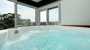 A hot tub with a view of trees and mountains through large windows. - Paraíso Azul do Rosa - IMB004 (Imbituba)