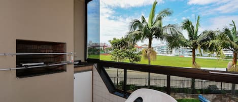A balcony with a view of a grassy area, palm trees, and a distant building.