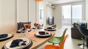 Un coin repas avec une table ronde prévue pour quatre personnes, un téléviseur et un balcon avec vue.