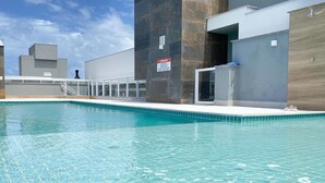 Une piscine à l’eau d’un bleu cristallin, une terrasse carrelée et un panneau indiquant qu’il s’agit d’un espace public.