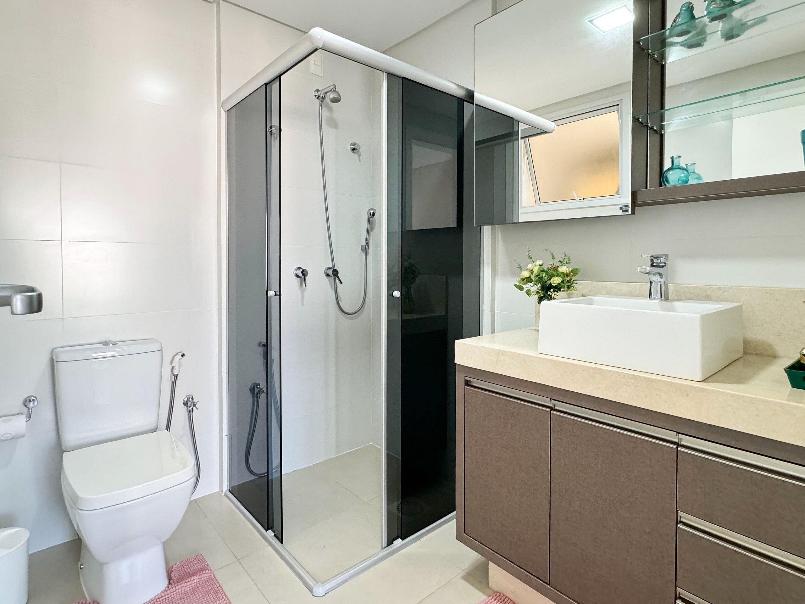 A modern bathroom with a glass-enclosed shower, a white sink, and a mirror above the vanity.