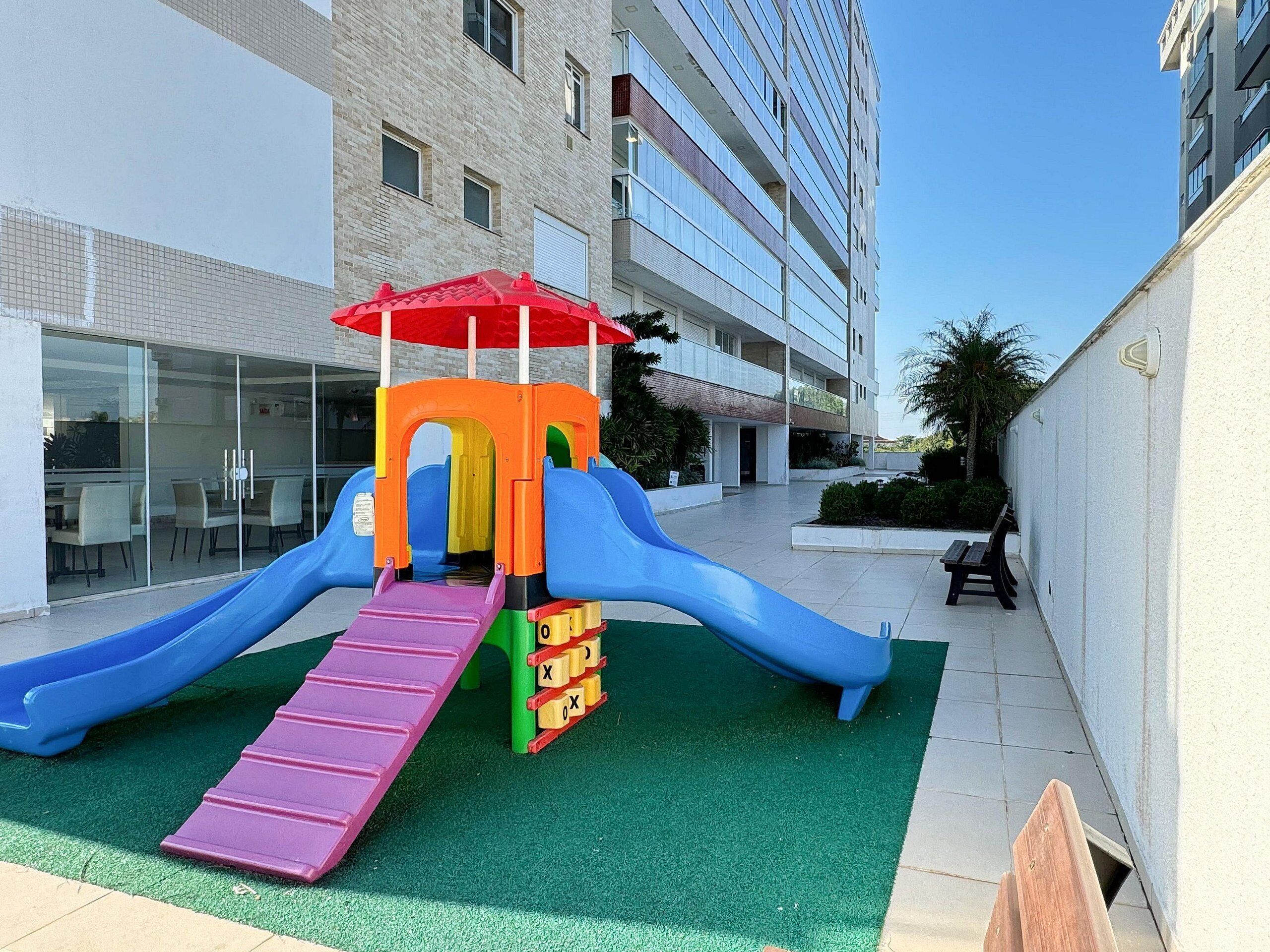 A playground with slides and a climbing structure in an urban setting.