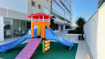 A playground with slides and a climbing structure in an urban setting.