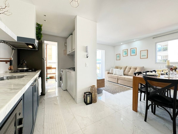A modern kitchen with a built-in stove, a sink, and a dining area with a table set for two.