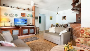 Una sala de estar con televisor, sofá y chimenea.