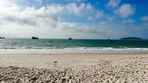Une plage où l’on peut voir des empreintes de pas et des bateaux sur l’eau.