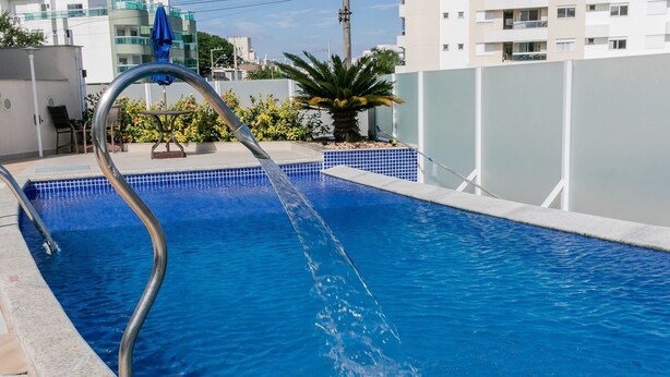 Una piscina con una escalera metálica y un borde de azulejos azules.