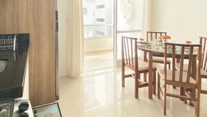 Una cocina moderna con estufa integrada y comedor con sillas de madera y mesa preparada para cuatro.