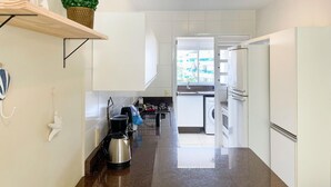Una cocina moderna con armarios blancos, un hervidor de acero inoxidable y un horno empotrado.