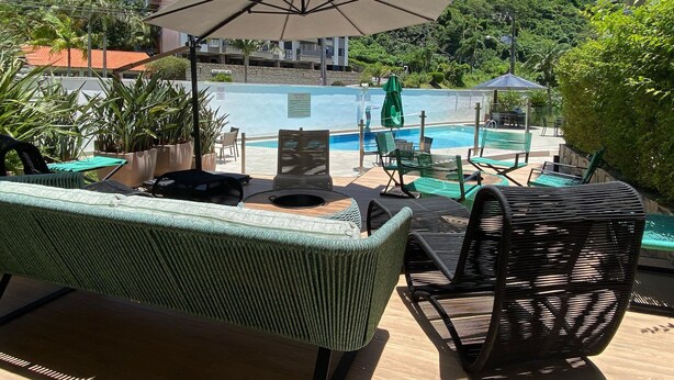 Un área junto a la piscina con sillas de descanso, una mesa y una sombrilla.