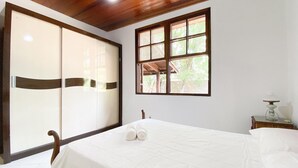 A bedroom with a bed, a wooden ceiling, a window, and a nightstand.