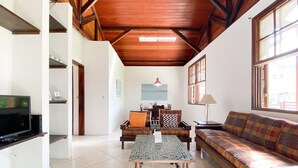 A spacious living area with a wooden ceiling, a sofa, a coffee table, and a television.