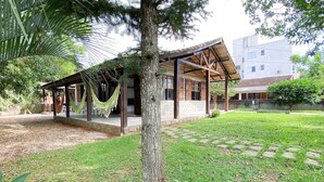 A covered outdoor area with a wooden structure, stone pathway, and a tree.