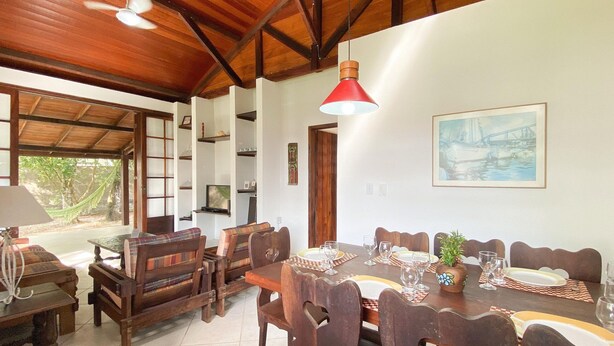 A dining area with wooden furniture, a red pendant light, and a painting on the wall.