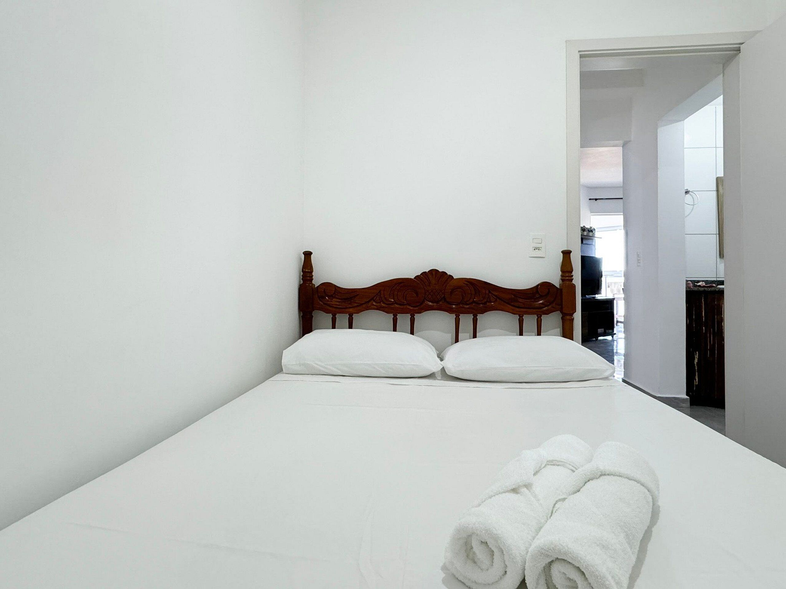 A small, neatly made bed with a wooden headboard in a minimalistic room.