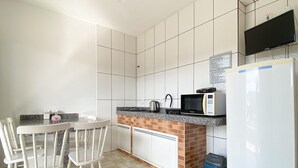 Una cucina con mobili bianchi, un piano di lavoro in granito, un forno a microonde, un bollitore e un frigorifero.