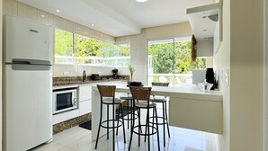 A modern kitchen with a central island, bar stools, a refrigerator, and a stove.