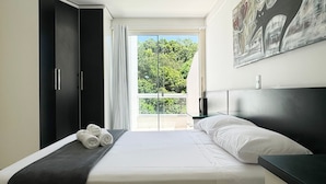 A modern bedroom with a large bed, a wardrobe, and a painting on the wall.