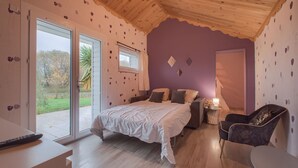 Un dormitorio con cama, una silla, una mesa y un ventanal.