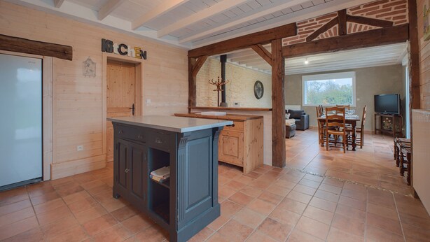 Una cocina amplia con armarios de madera, una isla central y un comedor con mesa y sillas.