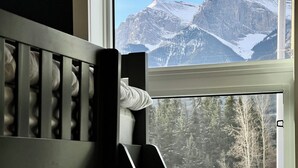 A room with a crib and a window overlooking snow-covered mountains. - Stunning Views | Brand-New Townhouse | Sleeps 11 AC +Hot Tub (Harvie Heights)