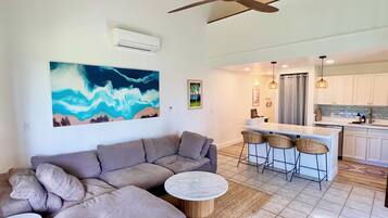 A modern living room with a sectional sofa, a round coffee table, and a large abstract painting.