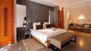 Een moderne slaapkamer met een groot bed, nachtkastjes, een bankje, een bank en een spiegel.