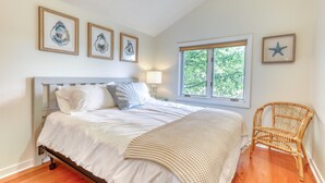 A bedroom with a bed, a window, and wall art.