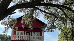 Ein zweistöckiges rotes Haus mit Balkon, Briefkasten und Auffahrt, auf der zwei Autos parken.